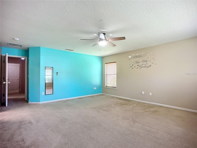 carpeted spare room featuring visible vents, a textured ceiling, baseboards, and a ceiling fan