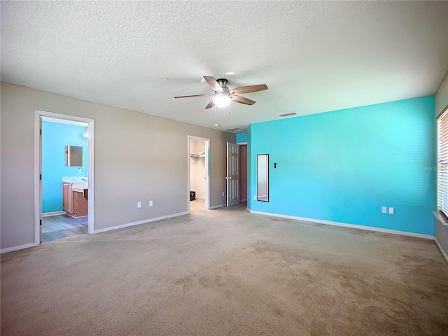 unfurnished bedroom with a walk in closet, carpet, visible vents, and a textured ceiling