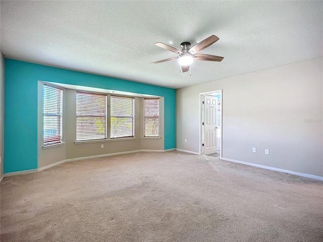 carpeted empty room featuring a ceiling fan, baseboards, and a textured ceiling