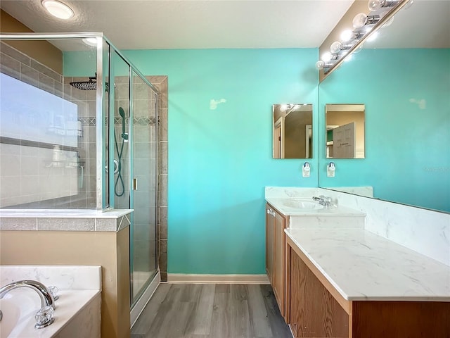 full bath featuring wood finished floors, a garden tub, a stall shower, and vanity