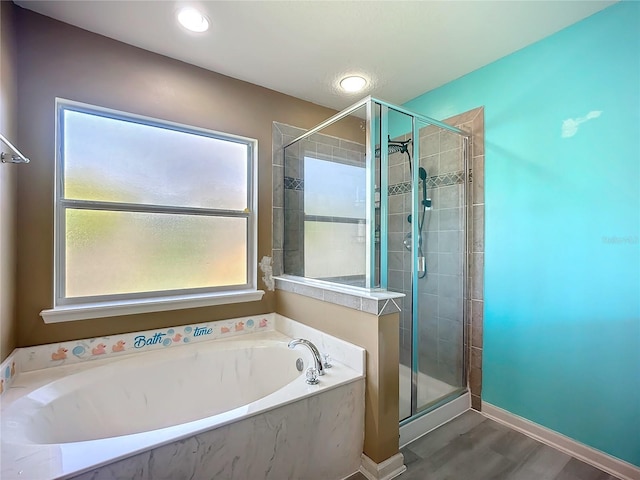 full bathroom featuring baseboards, wood finished floors, a garden tub, and a stall shower