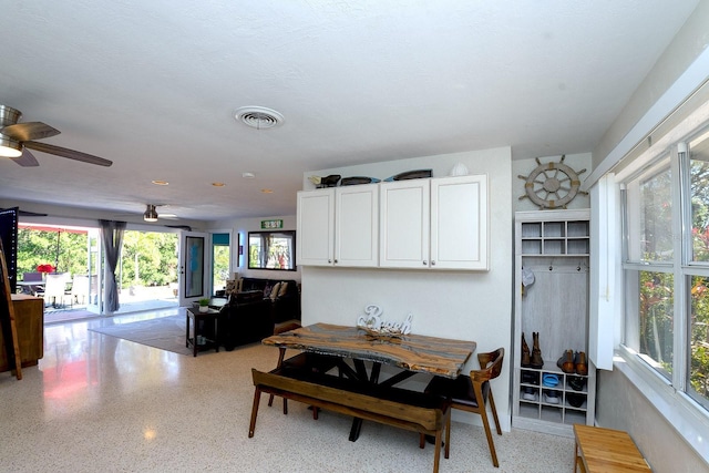 dining room with a ceiling fan, visible vents, and speckled floor