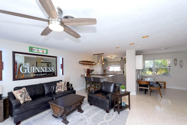 living room featuring light speckled floor, ceiling fan, and baseboards