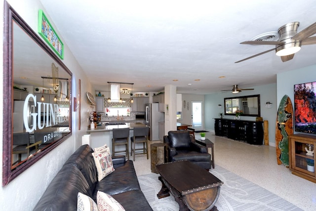 living room featuring light speckled floor, visible vents, and a ceiling fan