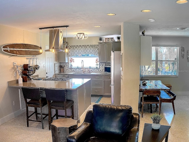 kitchen with plenty of natural light, a breakfast bar area, a sink, and gray cabinetry