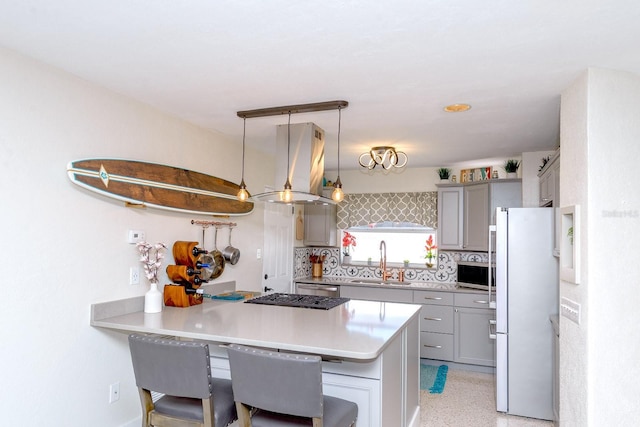 kitchen featuring stainless steel microwave, freestanding refrigerator, a peninsula, gray cabinetry, and a sink