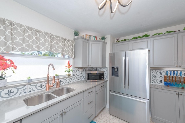 kitchen with light speckled floor, stainless steel appliances, light countertops, gray cabinetry, and a sink