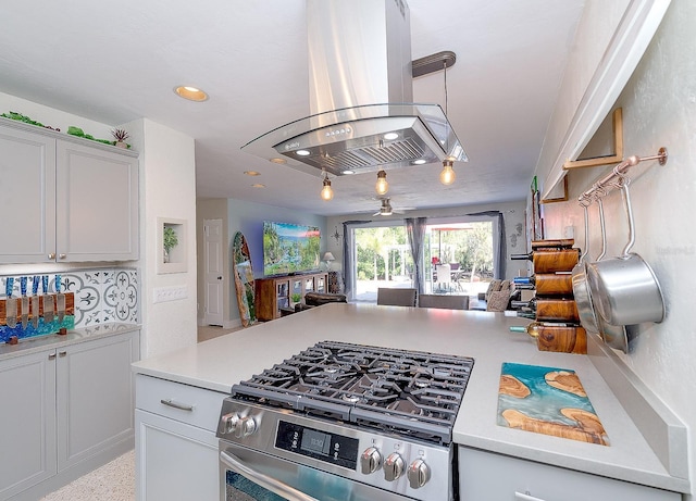 kitchen with open floor plan, light countertops, island exhaust hood, and stainless steel gas range oven