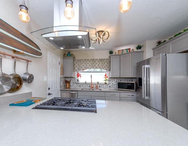 kitchen with decorative backsplash, gray cabinets, stainless steel appliances, light countertops, and a sink