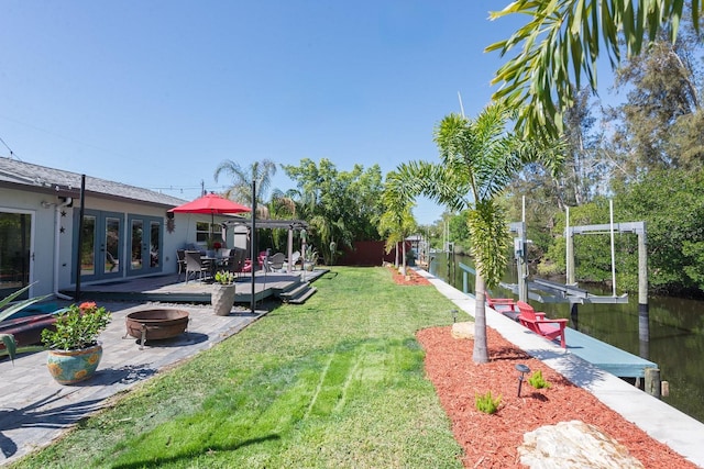 view of yard with french doors, boat lift, a patio area, a boat dock, and a fire pit