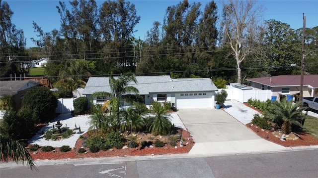 view of front of property featuring driveway, an attached garage, and fence