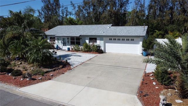 ranch-style house featuring a garage, concrete driveway, and a shingled roof