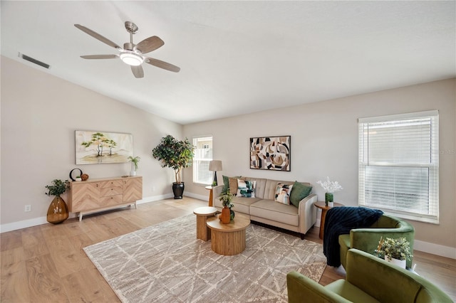 living area featuring lofted ceiling, visible vents, light wood-style flooring, and baseboards