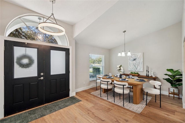 entryway featuring vaulted ceiling, baseboards, wood finished floors, and an inviting chandelier