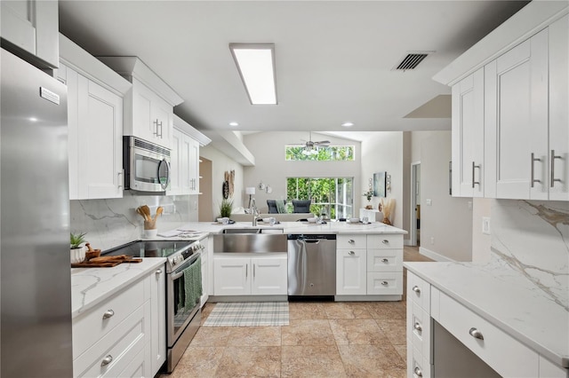 kitchen with a peninsula, a sink, visible vents, appliances with stainless steel finishes, and decorative backsplash