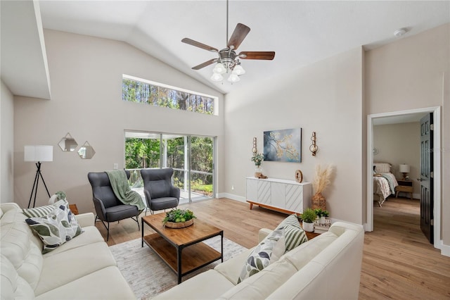 living room with light wood-style floors, ceiling fan, high vaulted ceiling, and baseboards