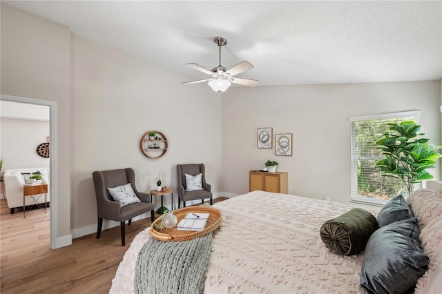 bedroom featuring lofted ceiling, ceiling fan, a textured ceiling, wood finished floors, and baseboards