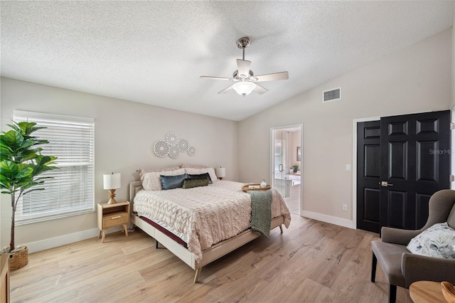 bedroom featuring lofted ceiling, light wood finished floors, visible vents, and a textured ceiling