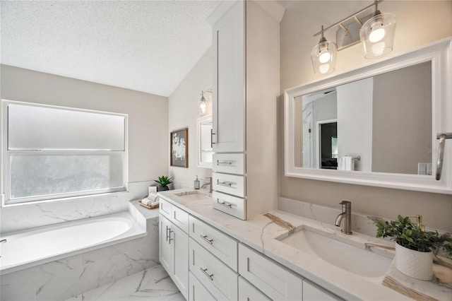 bathroom with a textured ceiling, a garden tub, a sink, marble finish floor, and double vanity