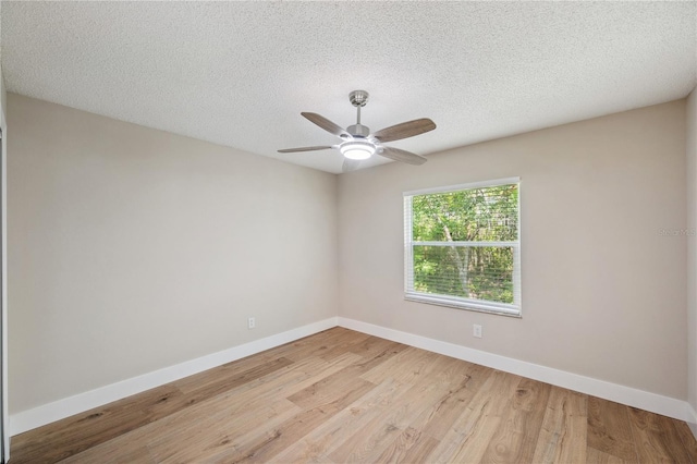 empty room with a textured ceiling, light wood finished floors, a ceiling fan, and baseboards