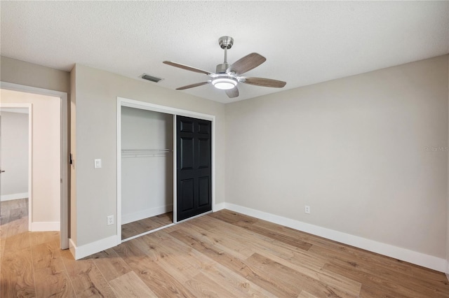 unfurnished bedroom with light wood finished floors, baseboards, visible vents, a textured ceiling, and a closet