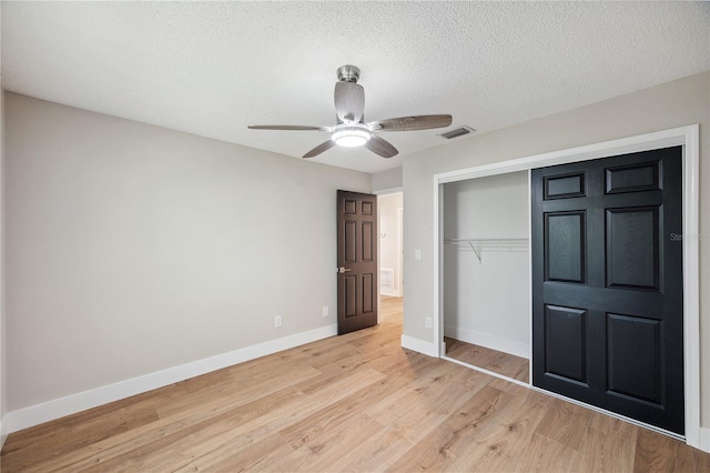 unfurnished bedroom featuring baseboards, visible vents, a textured ceiling, light wood-type flooring, and a closet