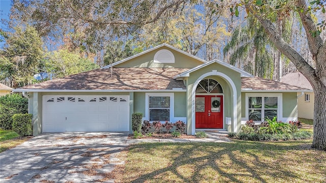 view of front of house with concrete driveway, roof with shingles, an attached garage, and stucco siding