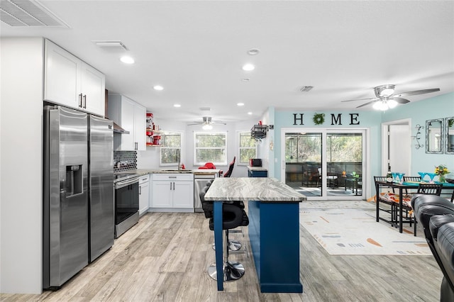 kitchen featuring stainless steel appliances, light wood-type flooring, visible vents, and a kitchen island