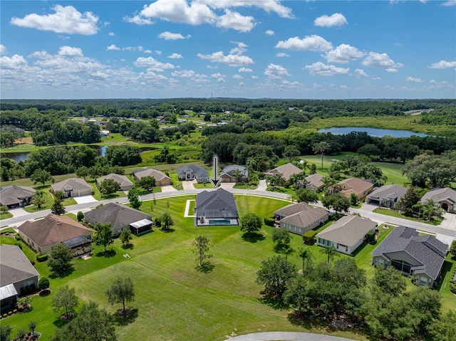 drone / aerial view with a residential view, a water view, and a wooded view