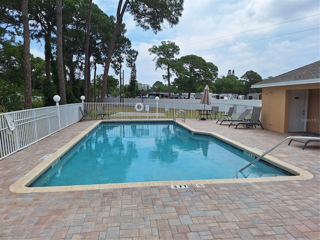 community pool with a patio area and fence