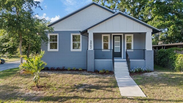 3902 E Henry Ave, Tampa, FL 33610 - bungalow-style home with a front yard, board and batten siding, and covered porch