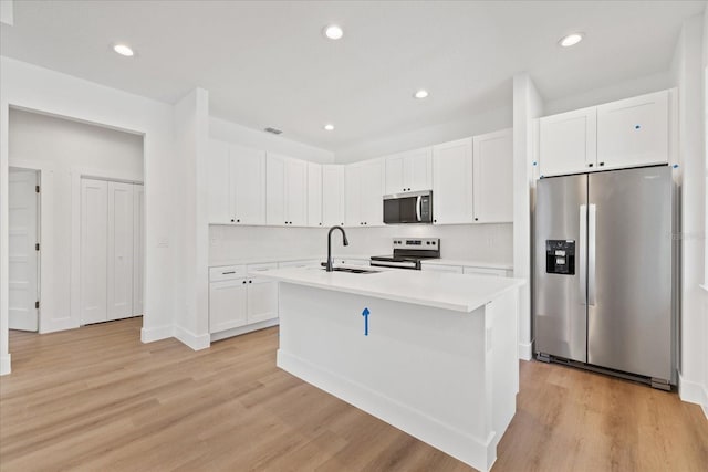 3902 E Henry Ave, Tampa, FL 33610 - kitchen featuring stainless steel appliances, a sink, light wood-type flooring, white cabinetry, and light countertops