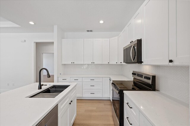 3902 E Henry Ave, Tampa, FL 33610 - kitchen featuring light wood finished floors, a sink, tasteful backsplash, light countertops, and appliances with stainless steel finishes