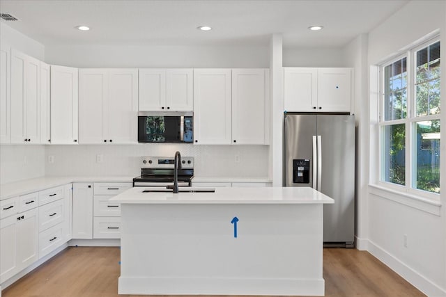 3902 E Henry Ave, Tampa, FL 33610 - kitchen with a sink, decorative backsplash, light wood-type flooring, white cabinetry, and appliances with stainless steel finishes