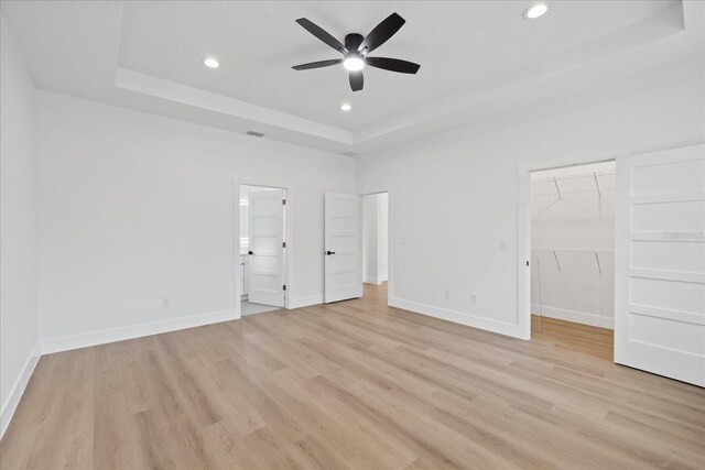 3902 E Henry Ave, Tampa, FL 33610 - unfurnished bedroom featuring light wood-style flooring, a tray ceiling, recessed lighting, and a walk in closet