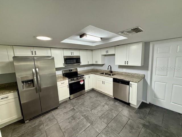 kitchen with visible vents, white cabinets, light stone counters, appliances with stainless steel finishes, and a sink