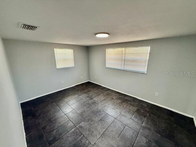 unfurnished room featuring baseboards and visible vents