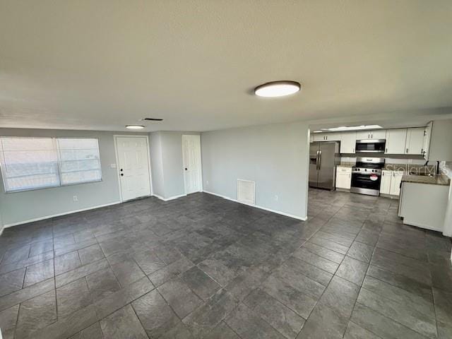 unfurnished living room with visible vents and baseboards