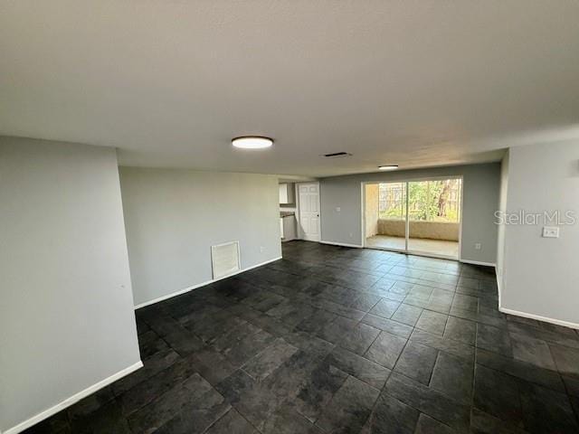 spare room featuring stone finish floor, visible vents, and baseboards