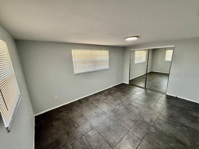 unfurnished bedroom with a closet and baseboards