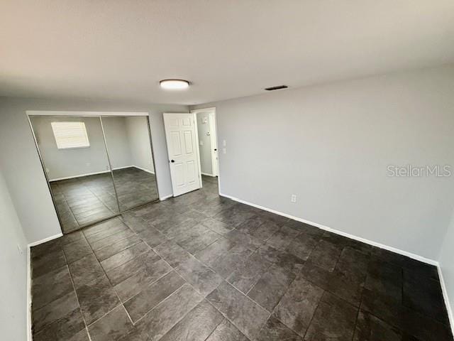 unfurnished bedroom with baseboards, visible vents, and a closet