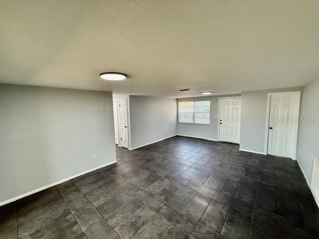 spare room with a textured ceiling and baseboards