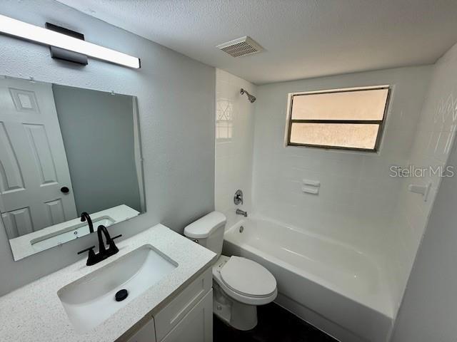 bathroom featuring visible vents, toilet, a textured ceiling, shower / tub combination, and vanity