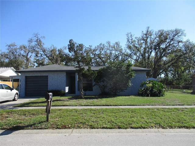 view of front of home with stucco siding, concrete driveway, fence, a garage, and a front lawn