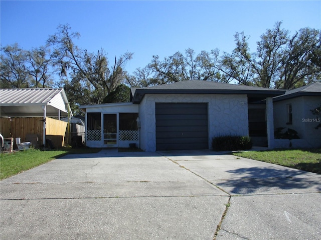 view of front of house with a garage, a sunroom, driveway, and fence