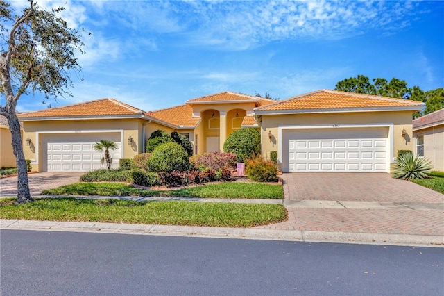 mediterranean / spanish-style house with a garage, decorative driveway, and stucco siding