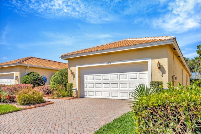 view of front of home with decorative driveway, a tile roof, and stucco siding