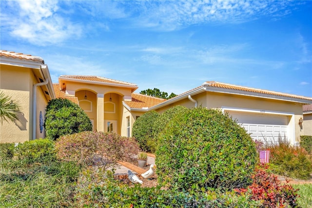 view of front of house featuring a garage, a tile roof, and stucco siding