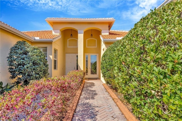 entrance to property with french doors, a tiled roof, and stucco siding