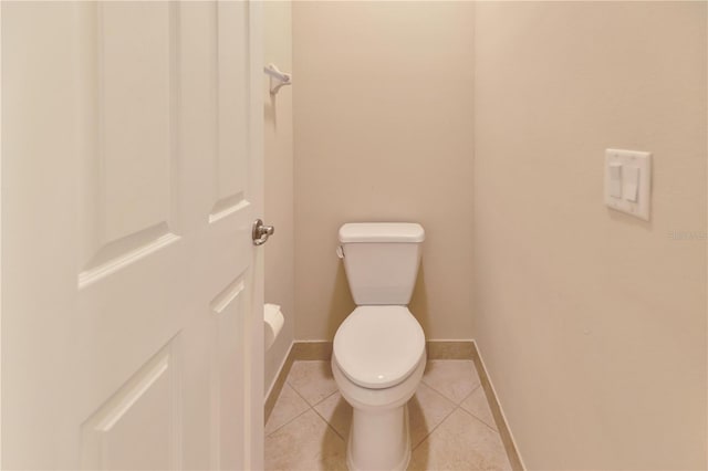 bathroom with baseboards, toilet, and tile patterned floors